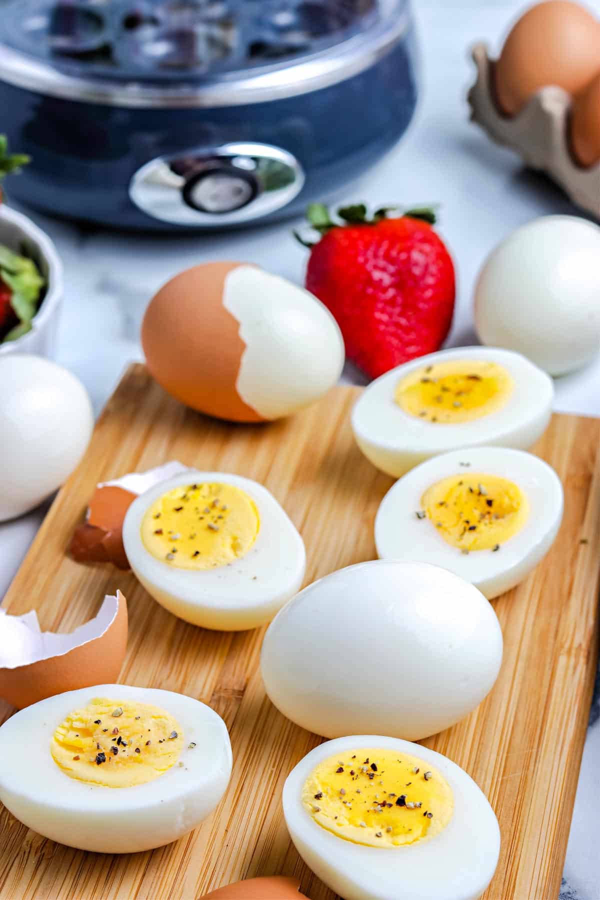 The finished hard boiled eggs on a wooden cutting board that were made in an egg cooker.