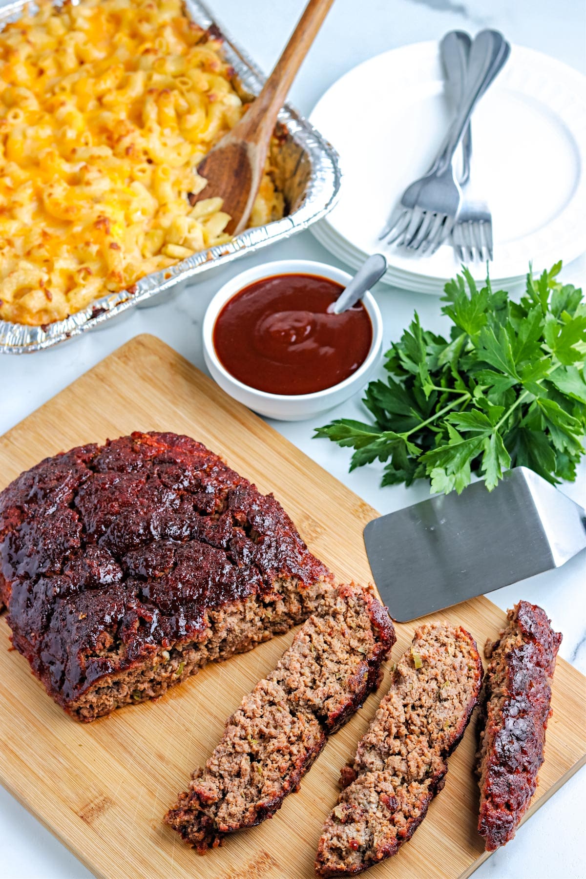 The finished smoked meatloaf on a cutting board with smoked Mac and cheese in the background.
