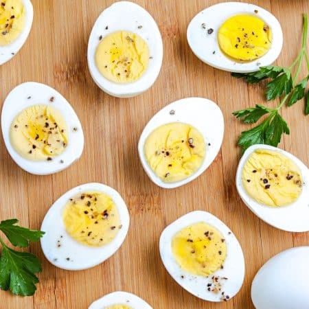 A close up picture of the finished Stovetop Hard Boiled Eggs Recipe on a wooden cutting board.