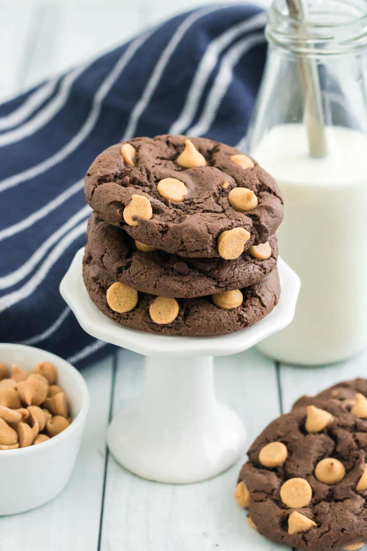 Three of the Chocolate Peanut Butter Chip Cookies on a white pedestal.