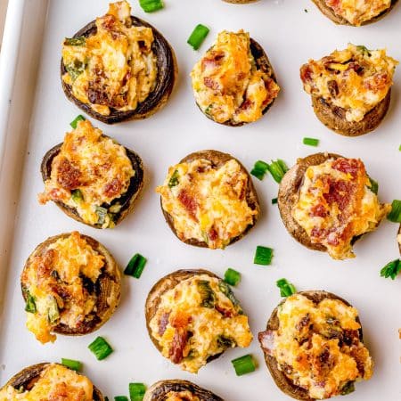 A close up picture of the finished Bacon Stuffed Mushrooms recipe on a baking tray.