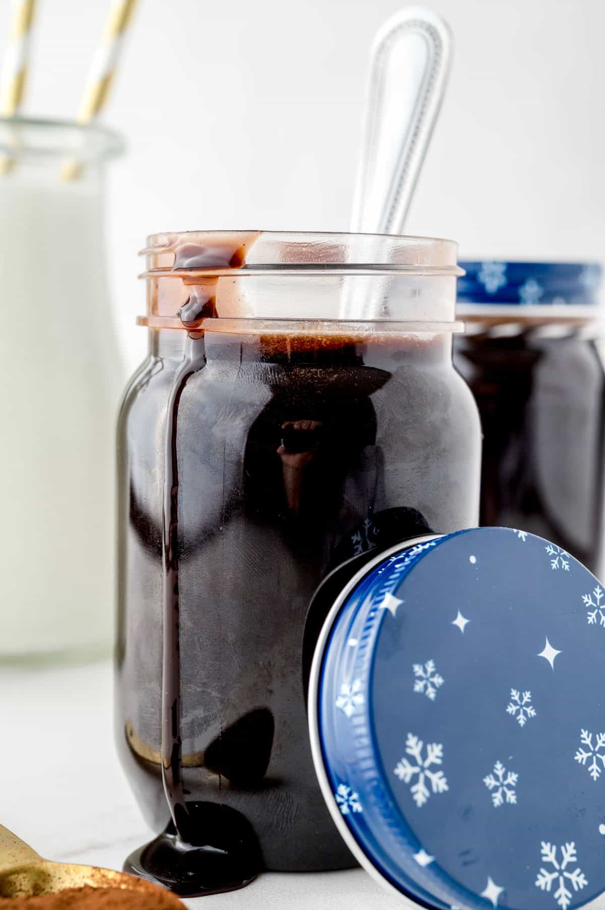 A jar full of the the finished Chocolate Syrup with a spoon in it.