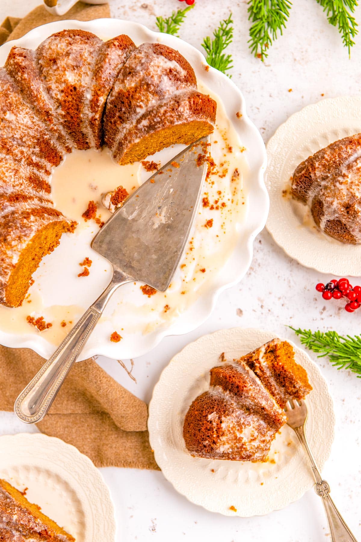 The finished Gingerbread Bundt Cake recipe cut into with slices on white plates around it.