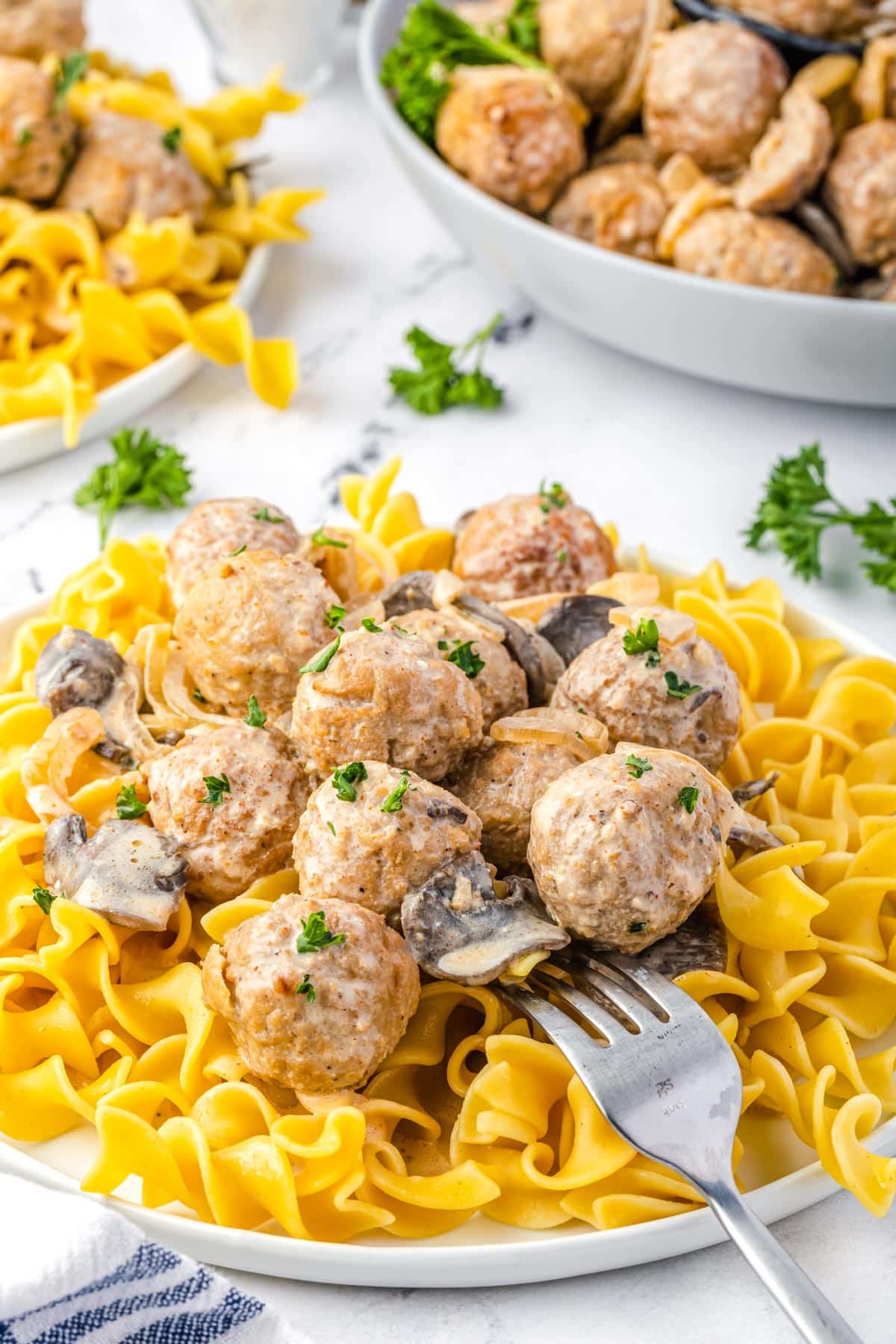 A fork digging the finished Meatball Stroganoff served over noodles.