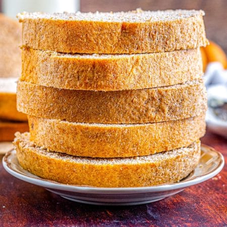 A close up picture of slices of the finished recipe for Honey Whole Wheat Bread stacked on top of each other.