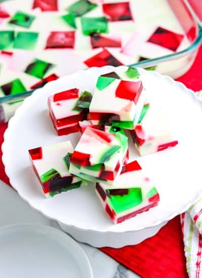 Squared of the Broken Glass Jello stacked on a white cake pedestal.