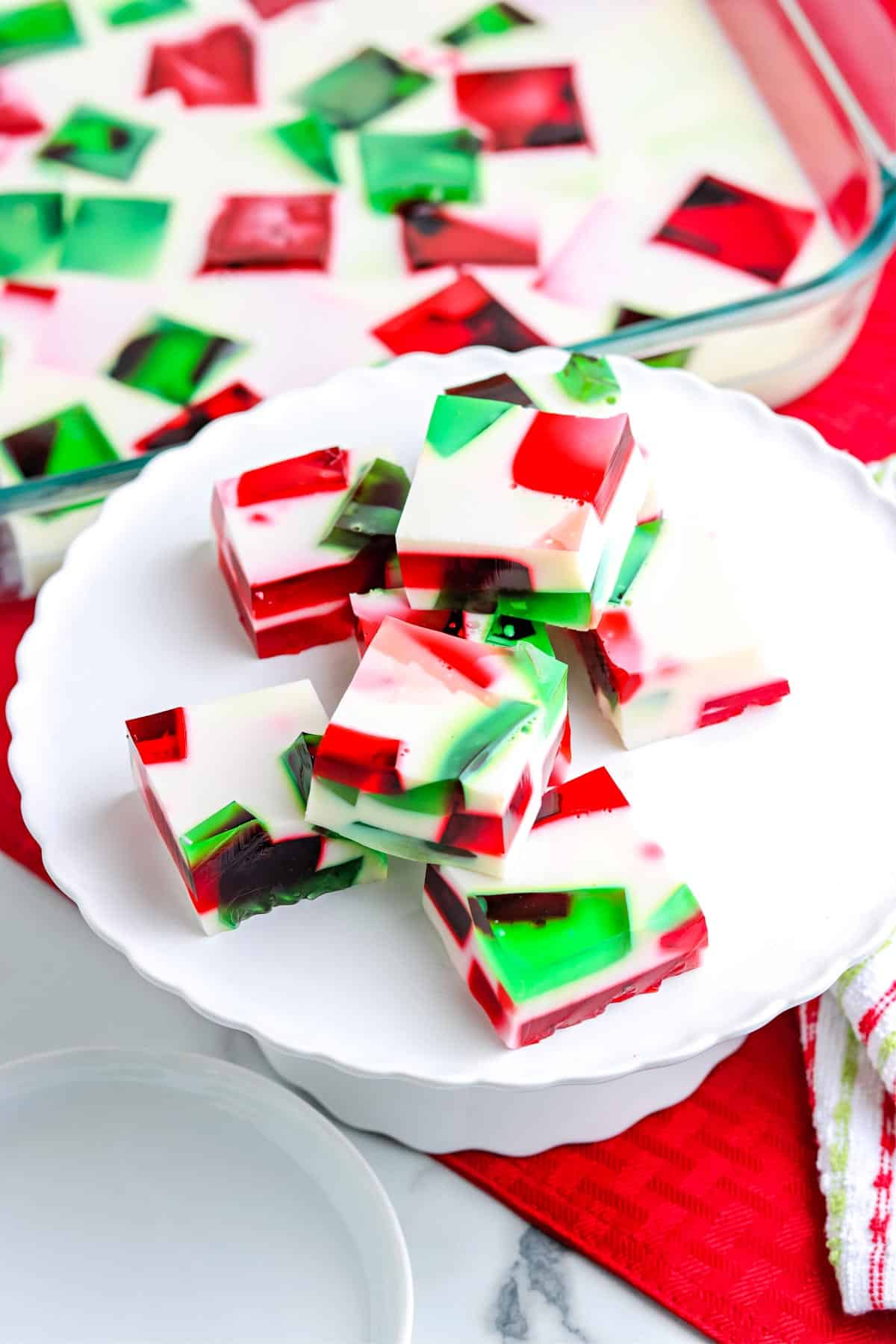 Squared of the Broken Glass Jello stacked on a white cake pedestal. 