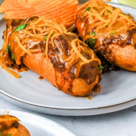 A close up picture of a Chili Cheese Corn Dog on a plate.