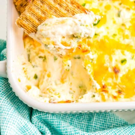 A close up picture of a cracker being dipped into the Jalapeno Cream here Dip.