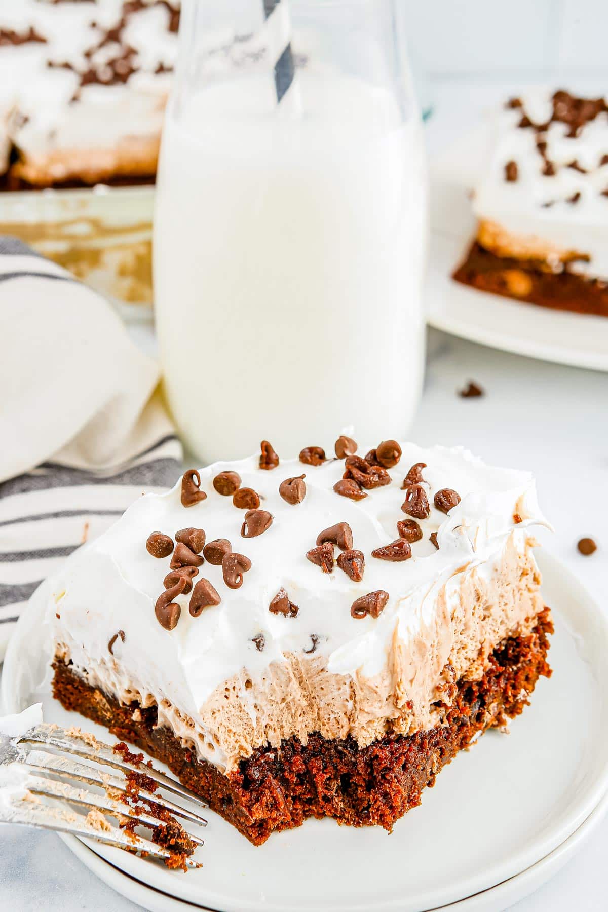 French Silk Brownies on white plate, one with a forkful taken out of it.