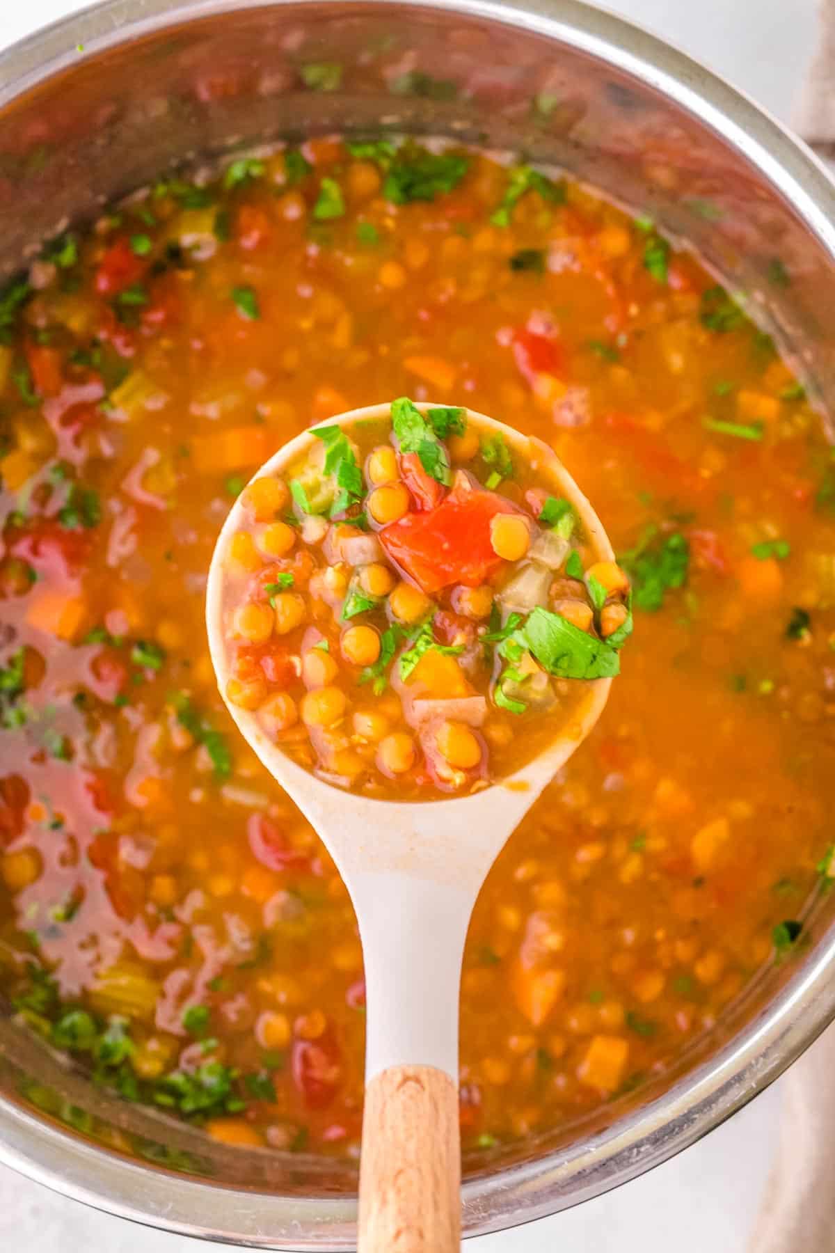 A wooden spoon scooping out of of the soup from the instant pot .