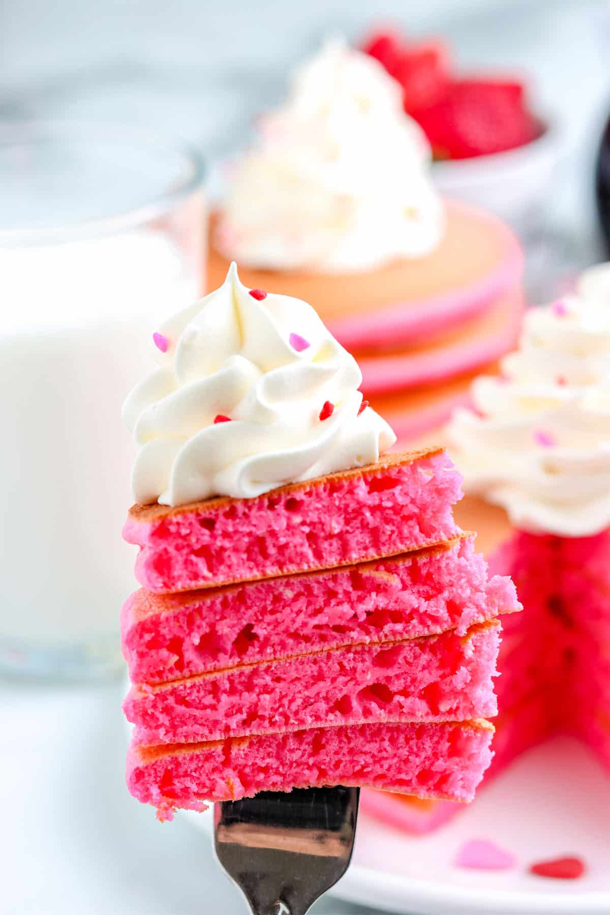 A fork taking a a forkful out of a stack of the Pink Pancakes.