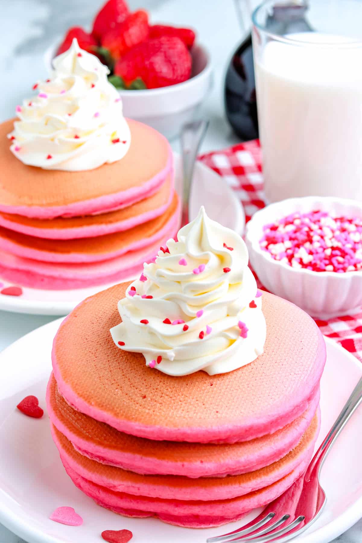 The finished Pink Pancake on a white plate with whipped cream and sprinkles.
