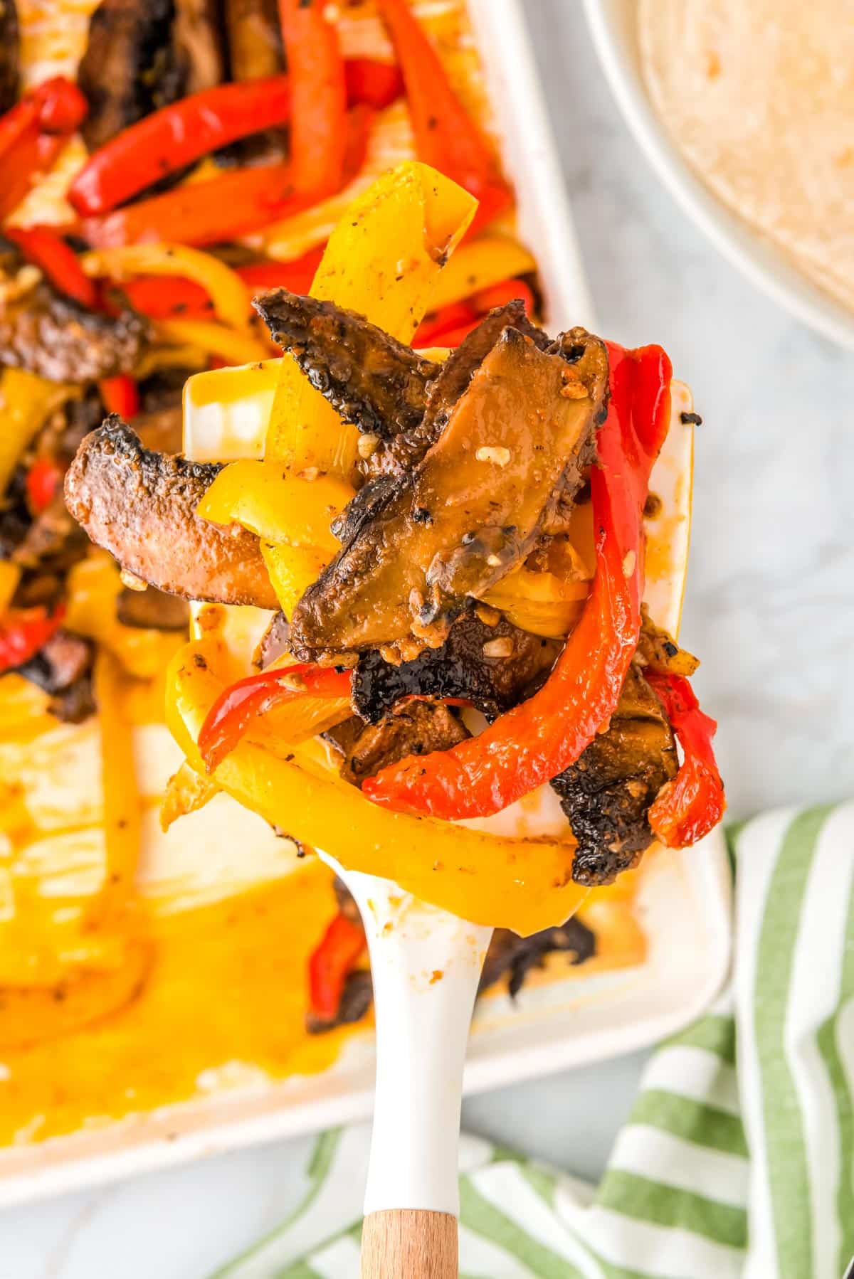 A spoon scooping up the mushroom taco filling from the sheet pan.
