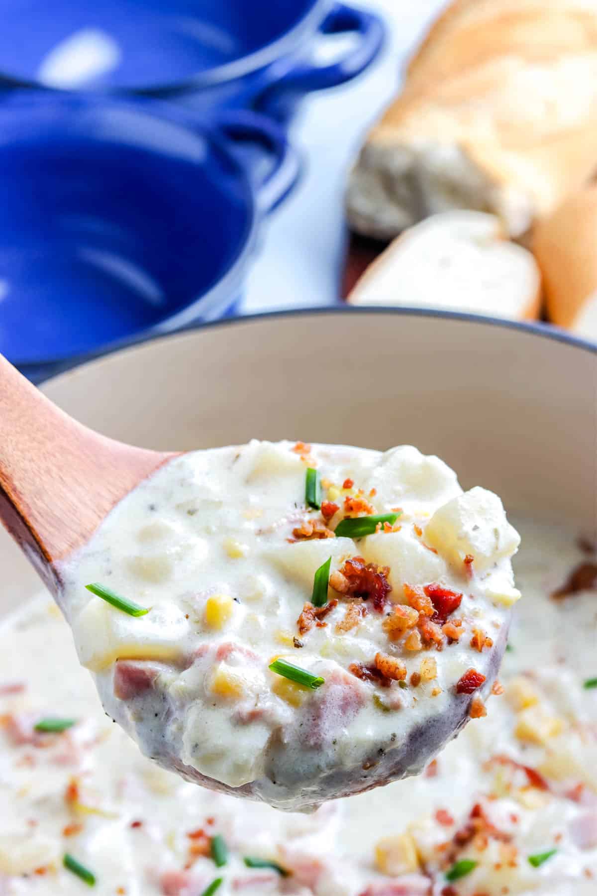 A close up picture of a ladle with the corn chowder and ham in it.