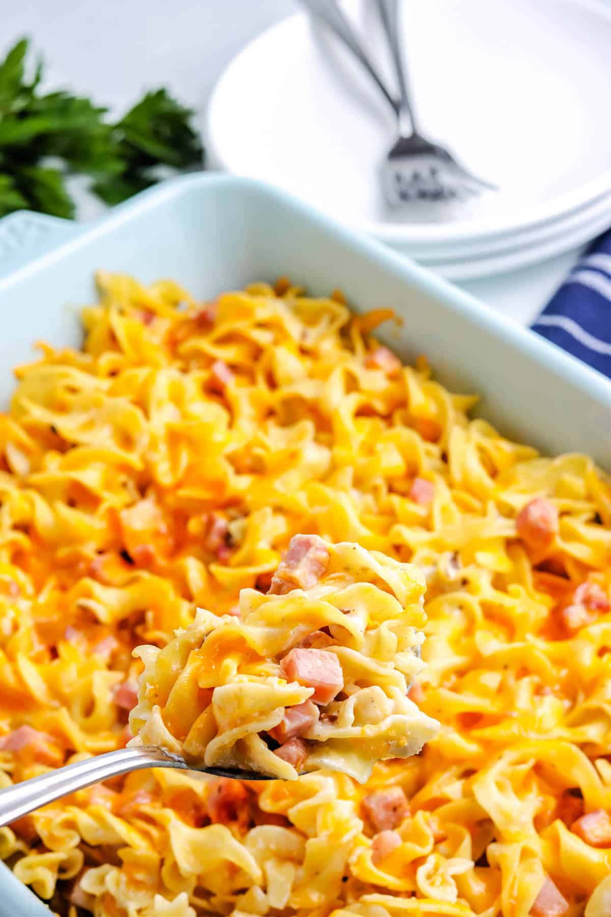 A spoon taking some of the Ham and Pasta Casserole out of the baking dish.
