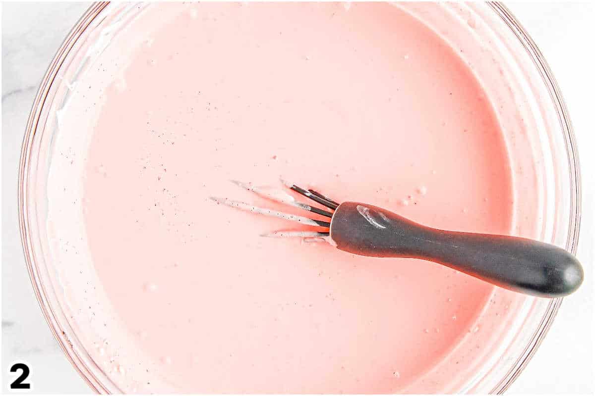Strawberry Jello and Cool Whip whisked together in a glass bowl.