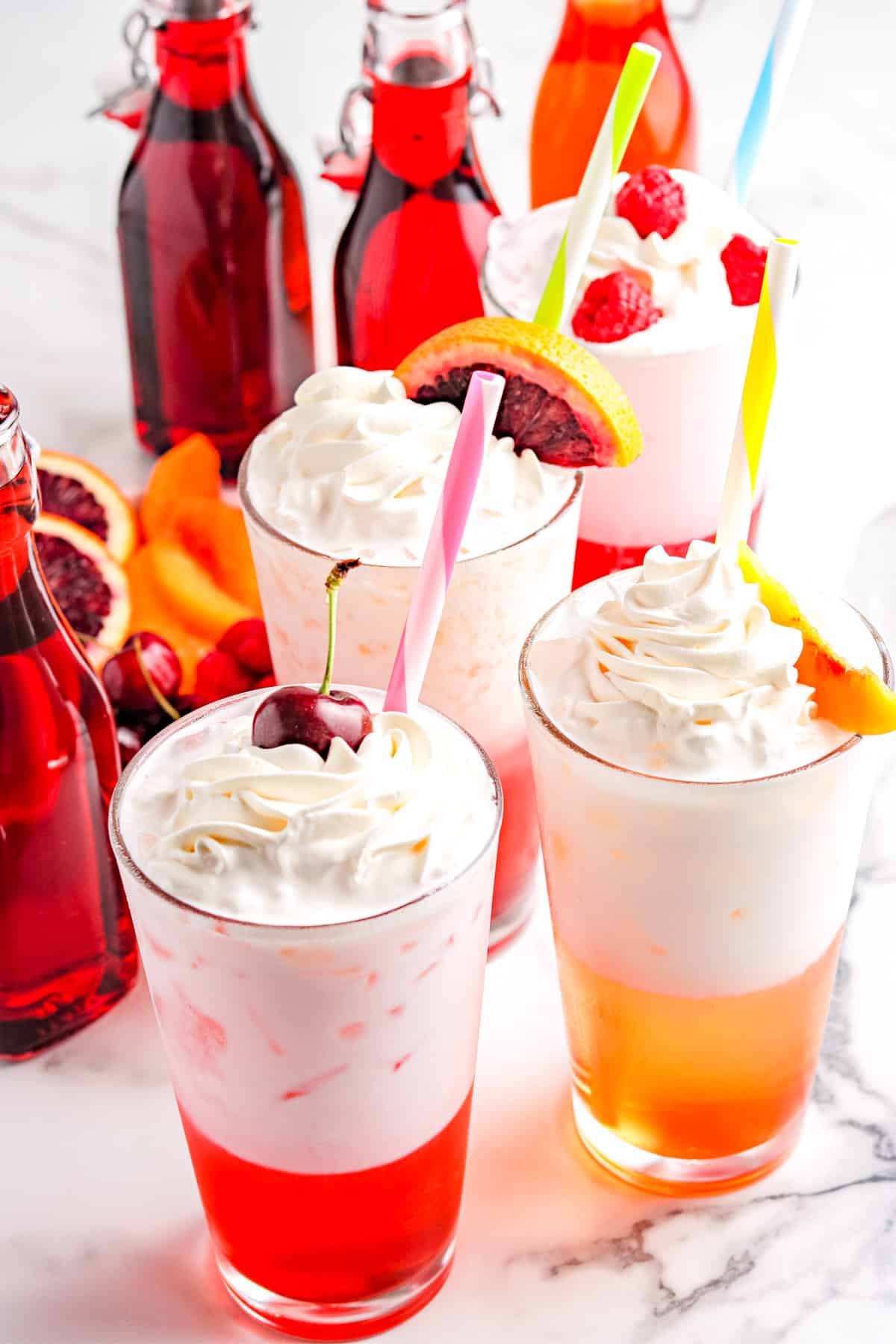 The finished Italian Cream Soda in clear glasses and garnished with whipped cream and fresh fruit. 