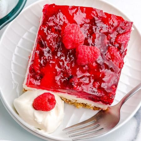 A close up overhead picture of a slice of Raspberry Pretzel Salad on a white plate.
