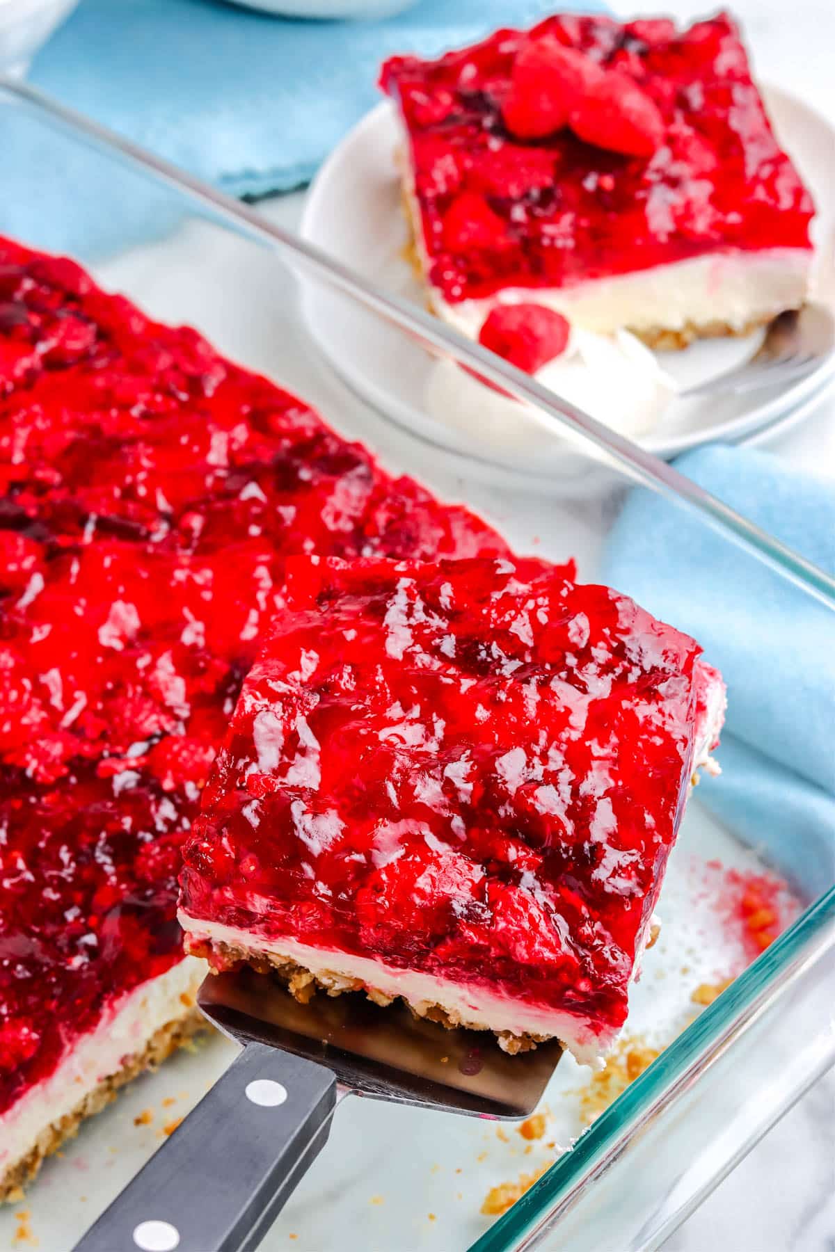 A slice of the Raspberry Jello Pretzel Salad being taken out of the casserole dish.
