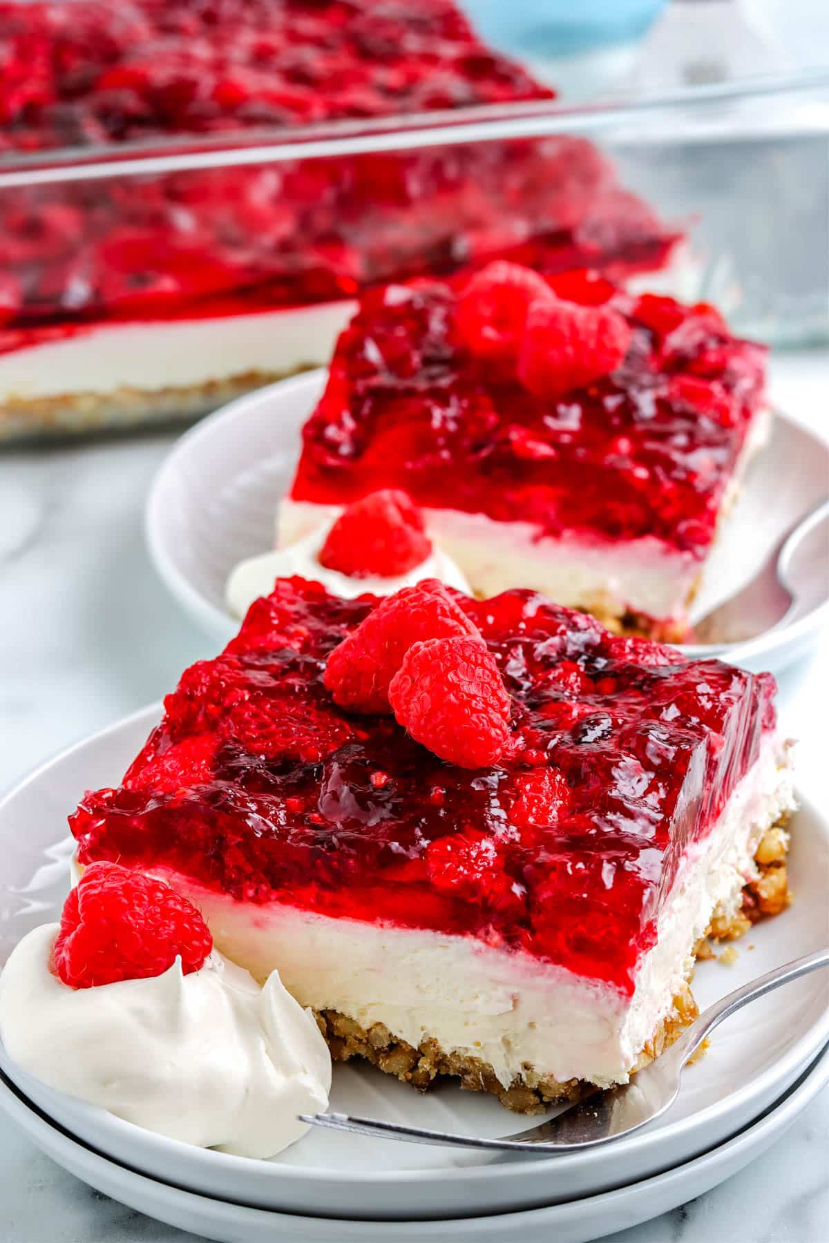 Slices of the finished Raspberry Pretzel Salad on white plates. 