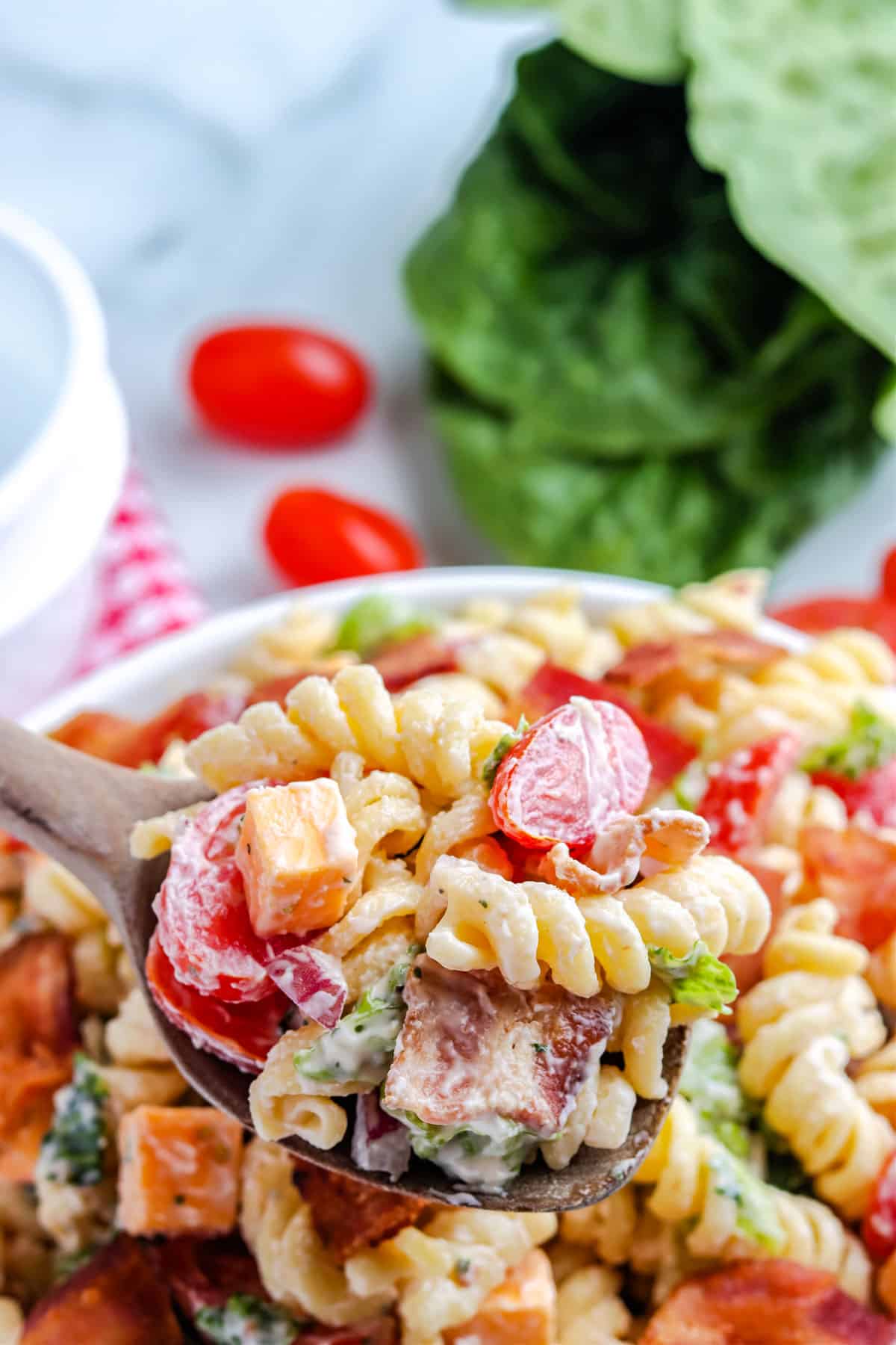 A wooden serving spoon picking up some of the pasta salad.