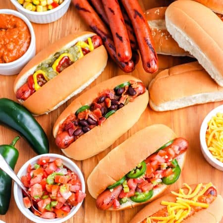 A close up of Grilled Hot Dogs on a Woden board.