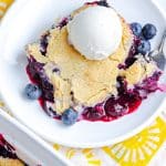 A scoop of Blueberry Cobbler on a white plate with ice cream.