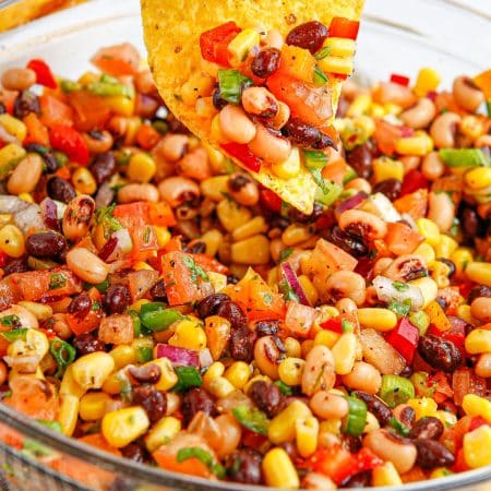 A close up picture of a tortilla chip with some of the Cowboy Caviar on it.