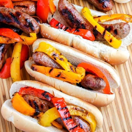 An overhead picture of three grilled Italian sausages in hoagie rolls.