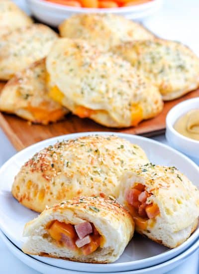 Two Ham and Cheese Hot Pockets on a plate and one broken in half.