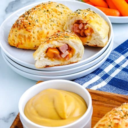 Two Ham and Cheese Hot Pockets on a plate. One is cut in half so you can se the inside.