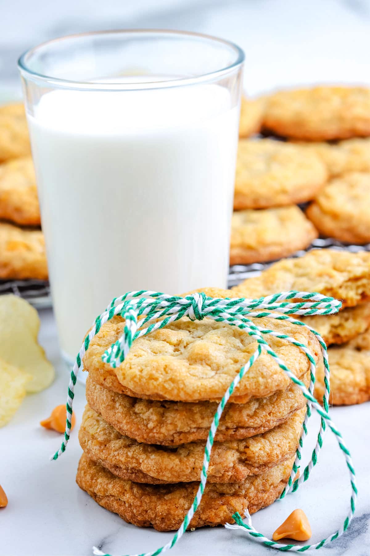 A stack of four Potato Chip Cookies with a glass of milk in the background.