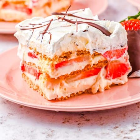 A close up picture of a slice of Strawberry Shortcake Icebox Cake on a pink plate.