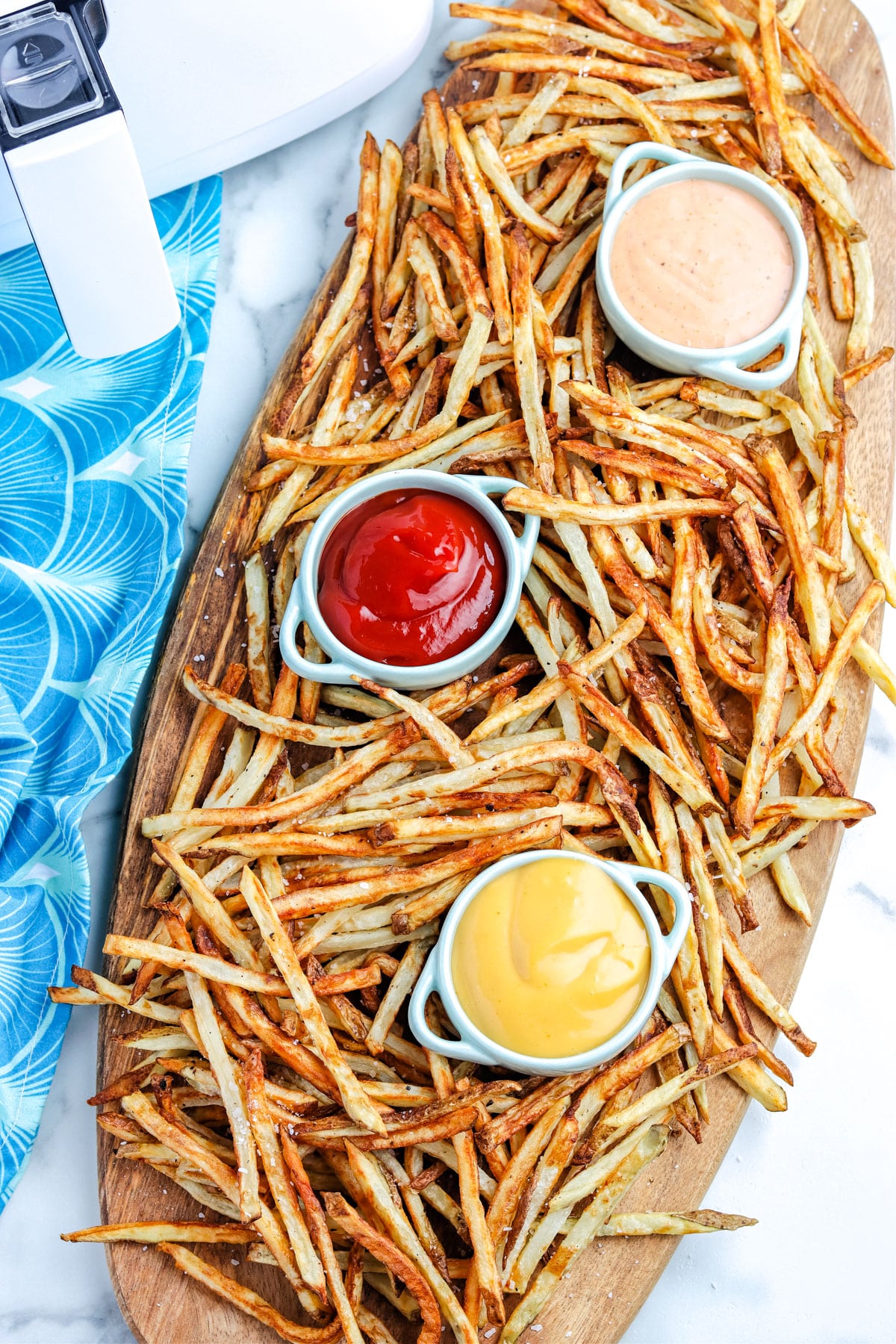 An overhead picture of the finished Air Fryer French Fries on a Woden serving board. 
