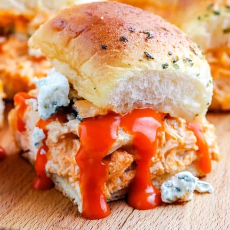 A close up of a Buffalo Chicken Slider on a Hawaiian roll that's dripping with Buffalo sauce.