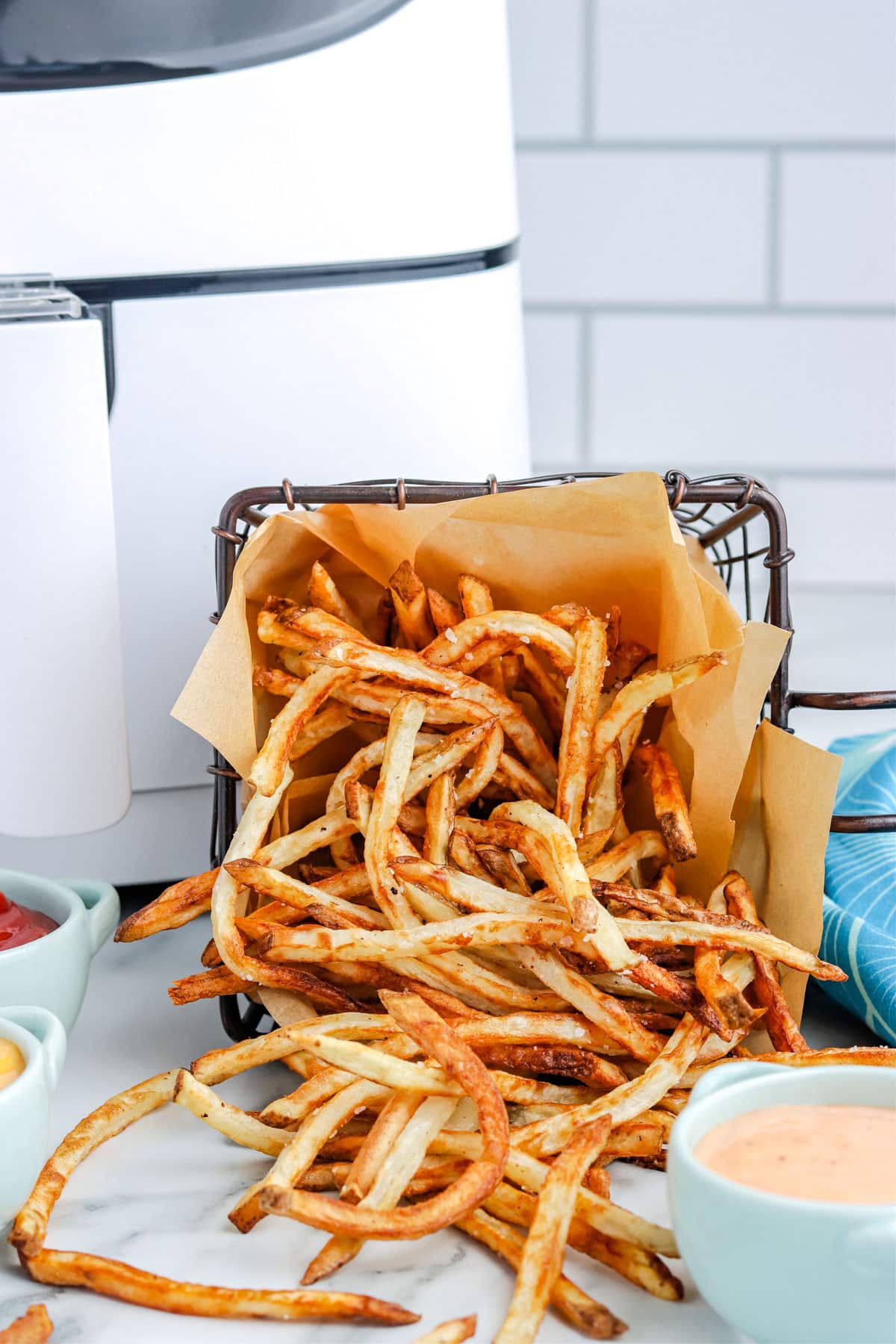 A basket of homemade Air Fryer French Fries in a little fryer basket.