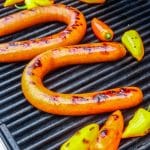 Kielbasa on a grill with char marks.