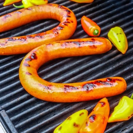Kielbasa on a grill with char marks.