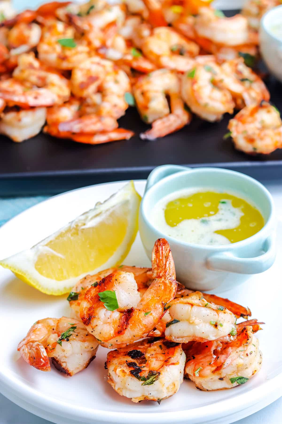 The finished Grilled Shrimp on a plate along with a dish of melted herb butter.