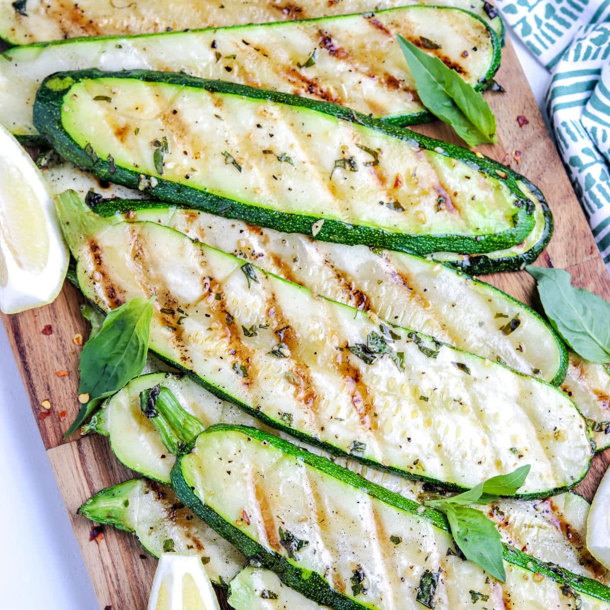 A close up of Grilled Zucchini strips on a wood cutting board.