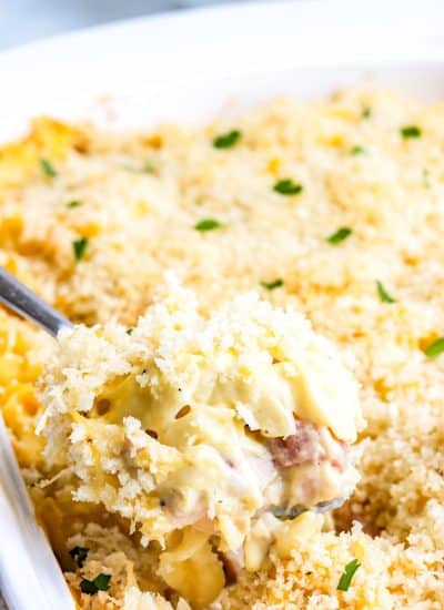 A spoon lifting some of the Chicken Cordon Bleu Casserole from the casserole dish.