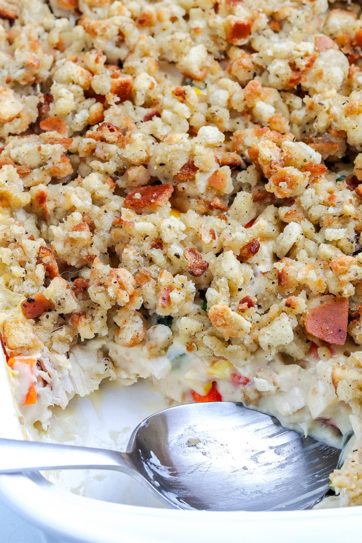 The finished casserole with a serving spoon in it scooping out some of it. 