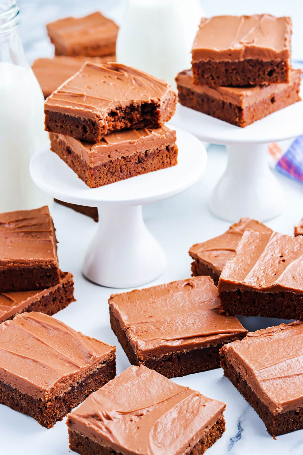 Frosted and cut brownies on a counter and little cake stand.