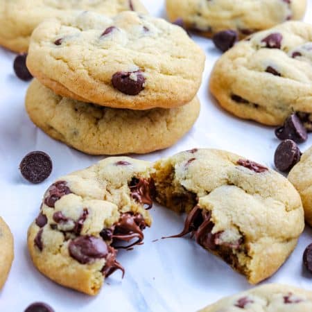 A close up of a cookie broken in half so you can see the melty chocolate chips.