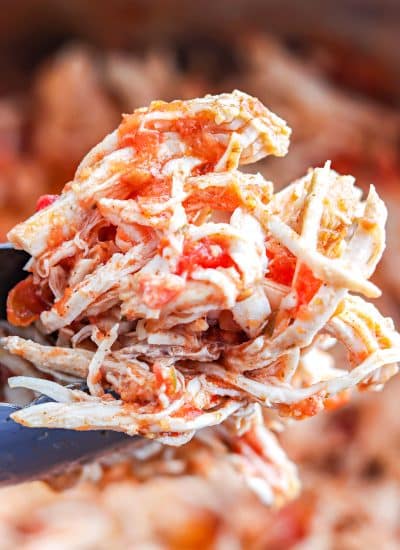 A close up of tongs lifting some Instant Pot Salsa Chicken.