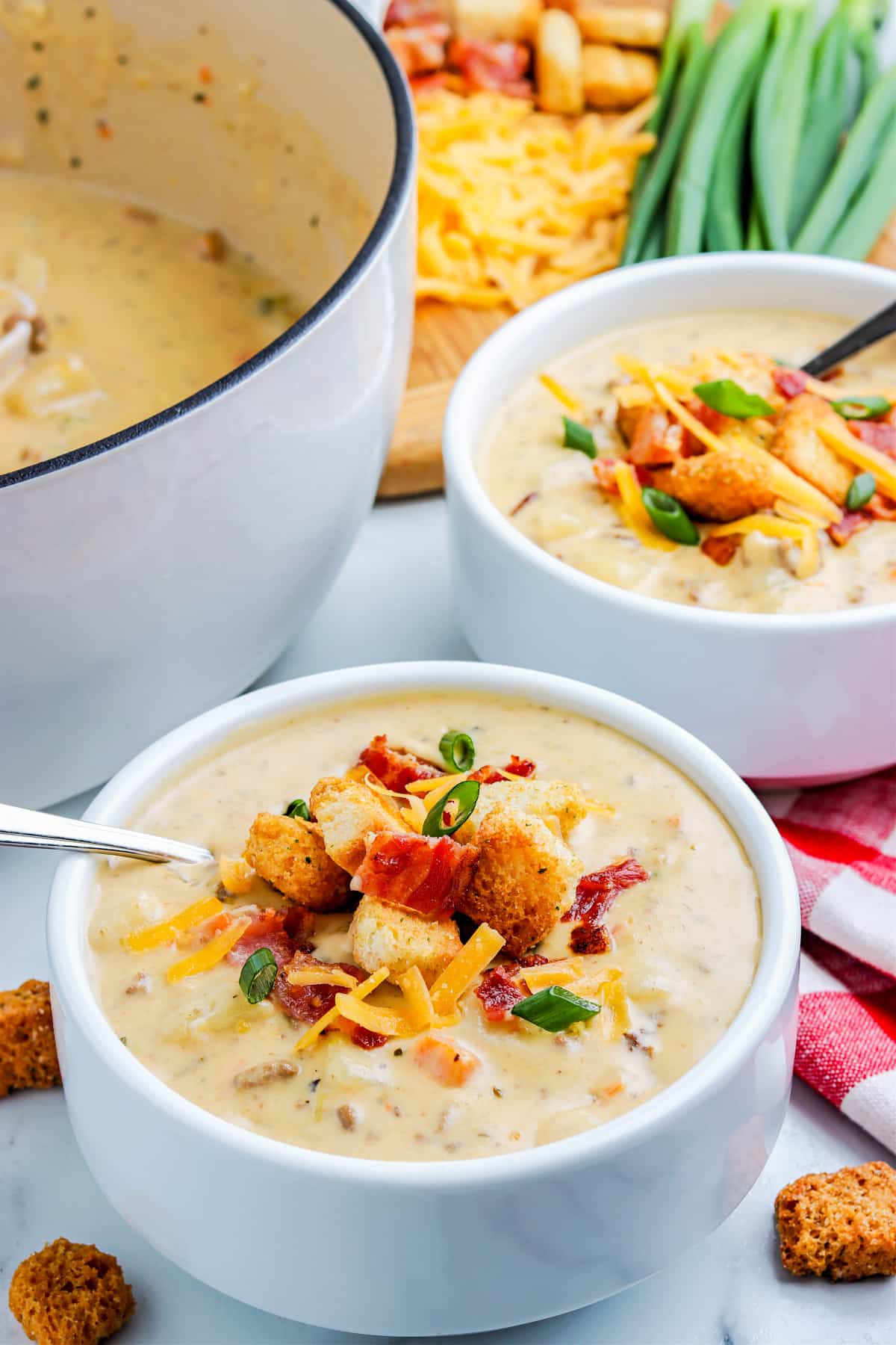 Cheeseburger Soup in a white bowl garnished with cheese, bacon, and croutons.