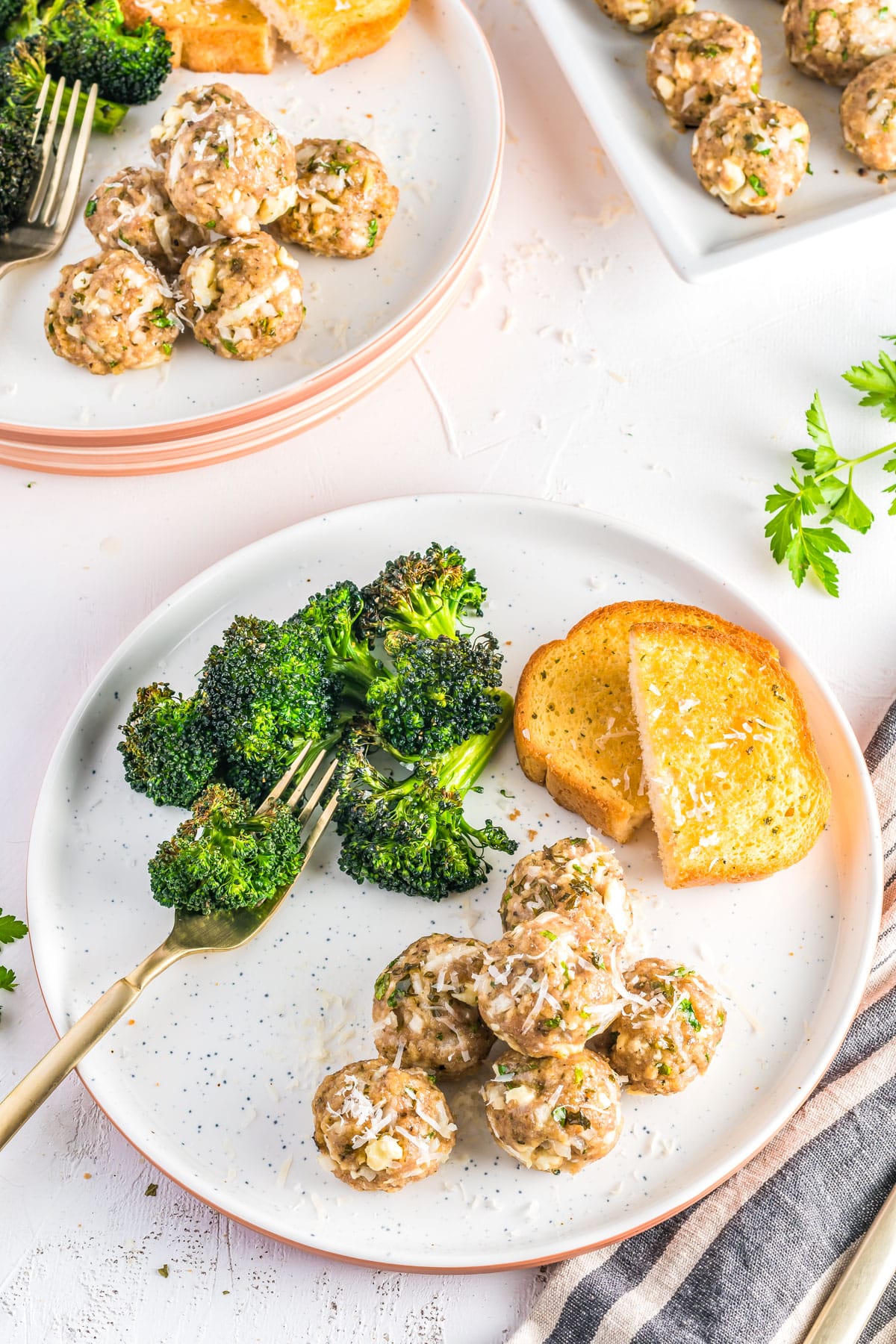 Baked Turkey Meatballs on a white plate with steamed broccoli and garlic bread.