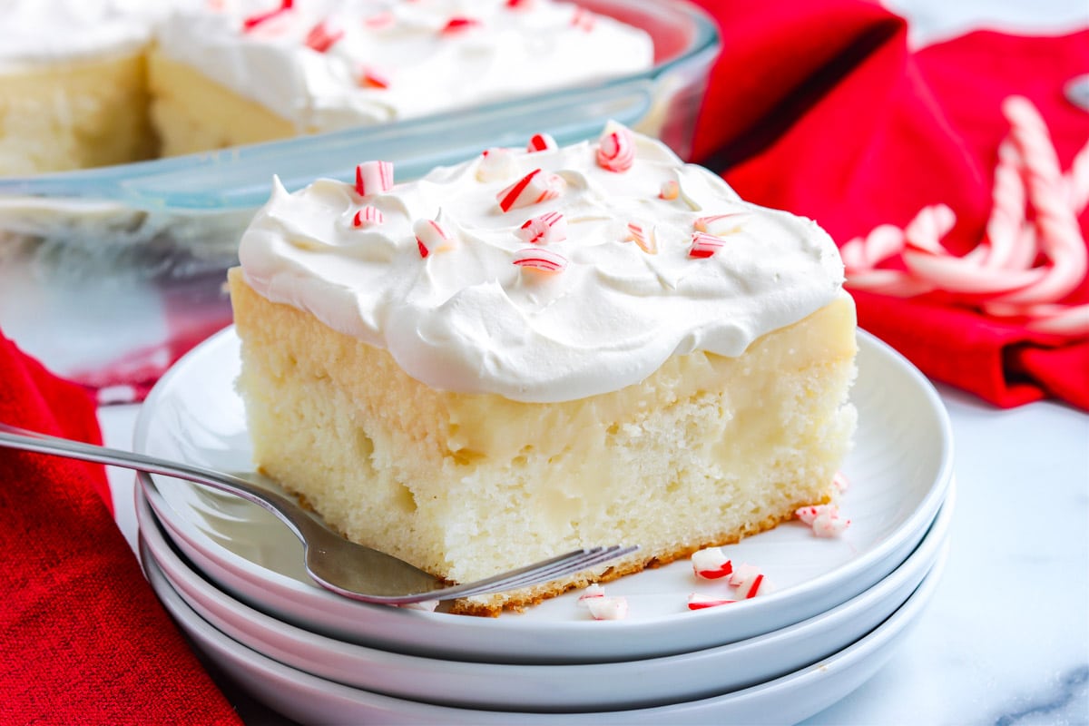 A close up of a slice of Peppermint Poke Cake on a white plate.