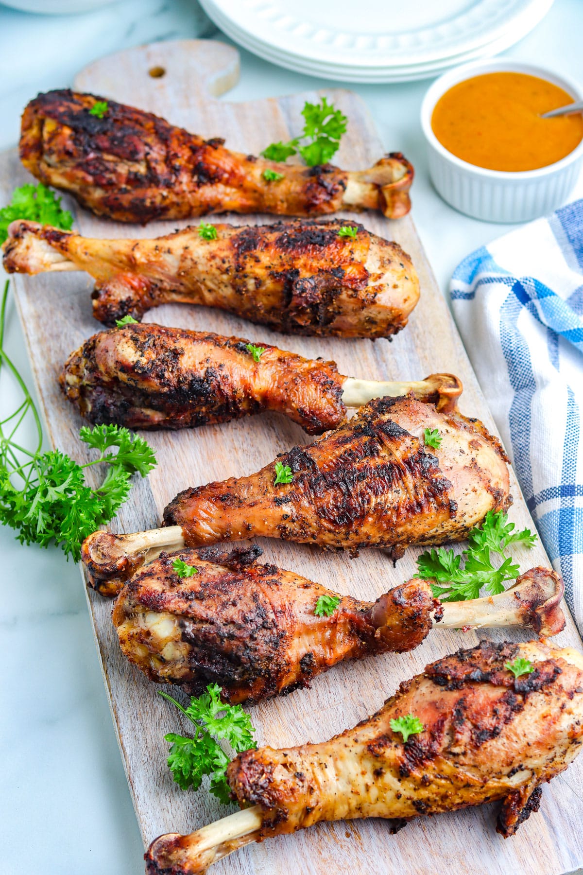 Six turkey legs that have been grilled and are on a wooden platter.